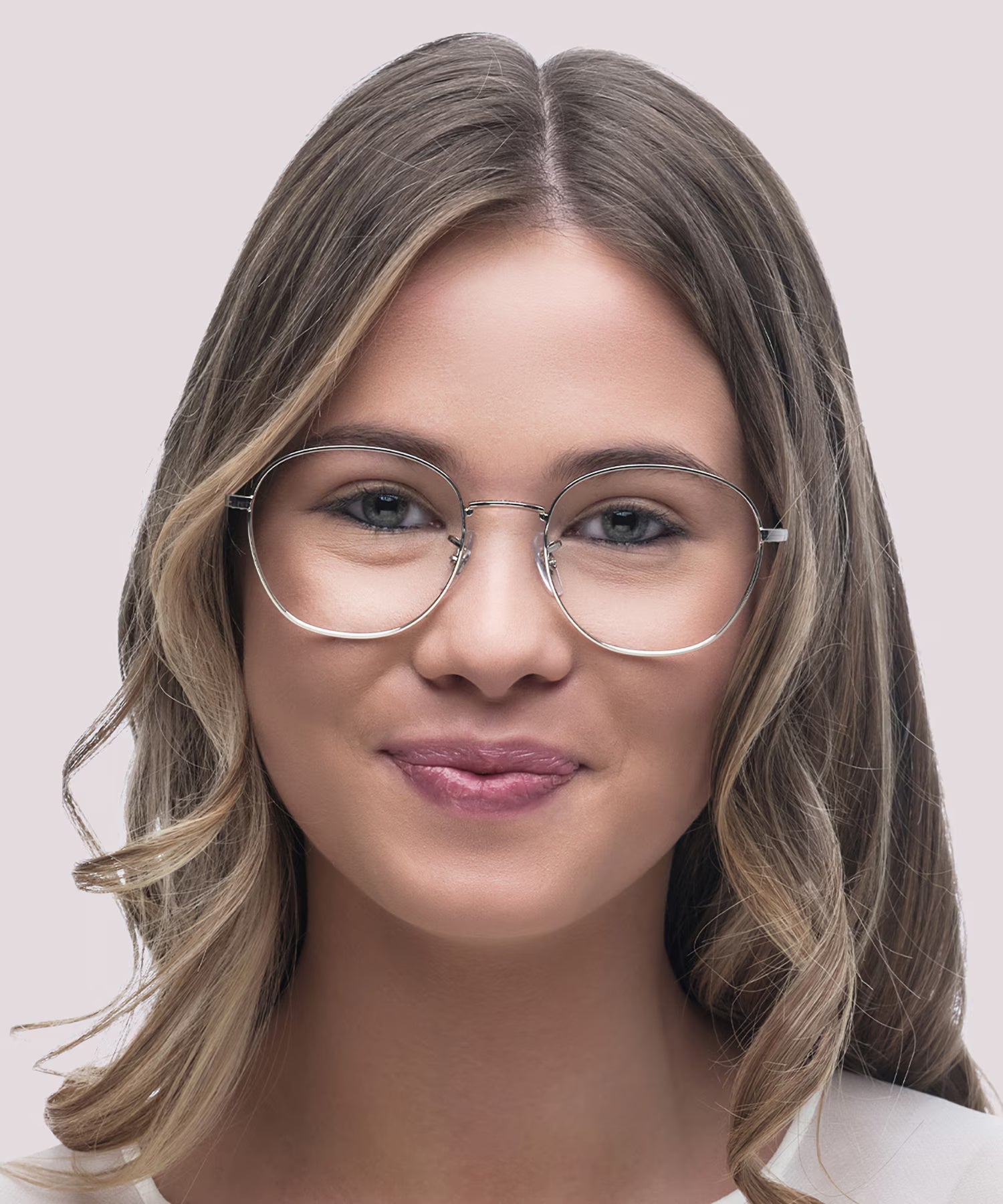 **Alt text:** "A close-up portrait of a woman wearing round, thin metal-framed Ray-Ban glasses, smiling softly at the camera. The glasses have a minimalist design, complementing her wavy, light brown hair and neutral background."